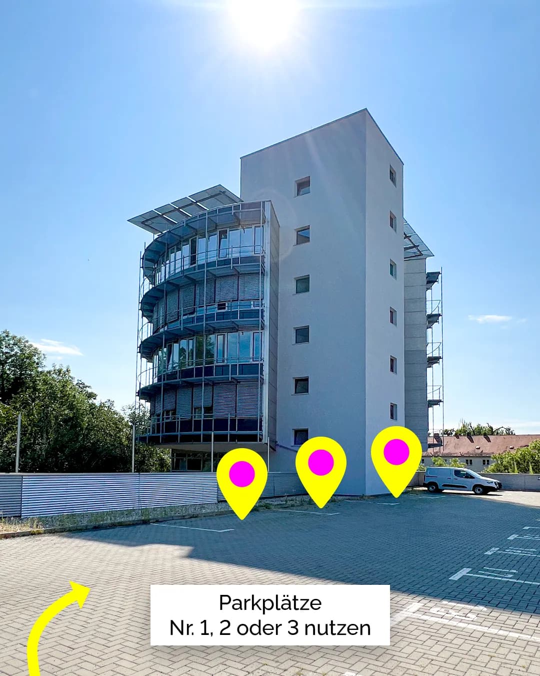 Ansicht eines modernen Bürogebäudes mit Parkfläche im Vordergrund. Drei gelbe Standortmarkierungen kennzeichnen ausgewählte Stellplätze, darunter der Hinweis „Parkplätze Nr. 1, 2 oder 3 nutzen“. Das Gebäude besitzt eine Glasfassade mit abgerundeten Balkonen, daneben einen schlichten weißen Turm.